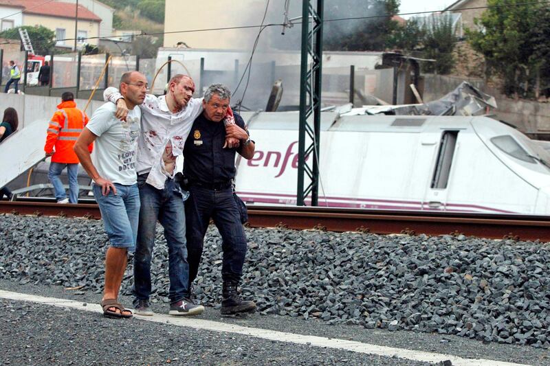 Rescue workers help a victim of a train crash near Santiago de Compostela, northwestern Spain, July 24, 2013. At least 56 people died after a train derailed in the outskirts of the northern Spanish city of Santiago de Compostela, the head of Spain's Galicia region, Alberto Nunez Feijoo, told Television de Galicia.  MANDATORY CREDIT.  REUTERS/Monica Ferreiros/La Voz de Galicia  (SPAIN - Tags: DISASTER TRANSPORT) SPAIN OUT. NO COMMERCIAL OR EDITORIAL SALES IN SPAIN. MANDATORY CREDIT *** Local Caption ***  PDH701_SPAIN-TRAIN-_0724_11.JPG