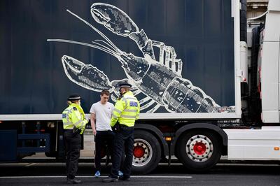 Police officers talk to a driver working in the shellfish industry who brought his truck to central London to protest against post-Brexit red tape and coronavirus restrictions, which they say could threaten the future of the industry, in London on January 18, 2021. / AFP / Tolga Akmen
