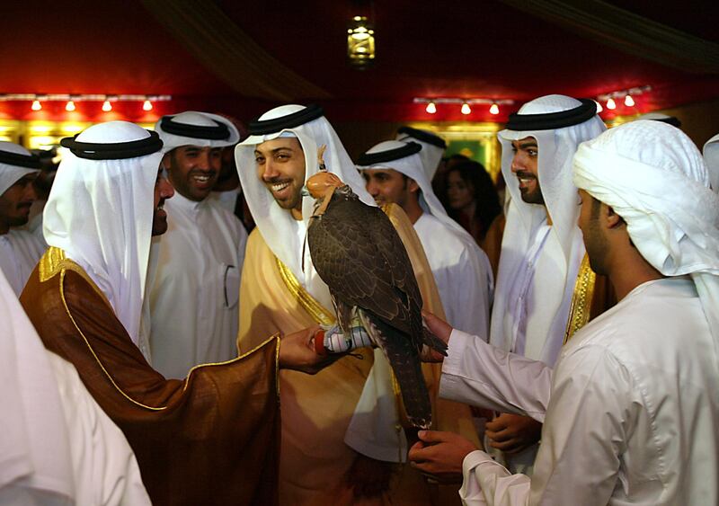 Sheikh Mansur bin Zayed (3rd L), chairman of the United Arab Emirates president's private office, smiles as he is shown a hunting falcon during the opening of the International Hunting and Equestrian Exhibition in Abu Dhabi 13 September 2004. More than 185 exhibitors from 21 countries are participating in the show. AFP PHOTO/Rabih MOGHRABI (Photo by RABIH MOGHRABI / AFP)