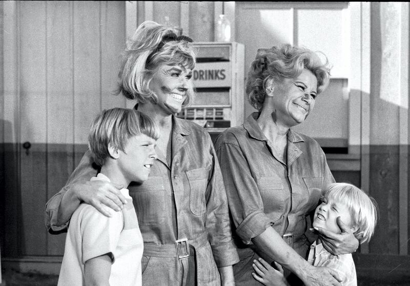 American actresses Doris Day, as Doris Martin, and Rose Marie, as Myrna Gibbons, with their faces dirty from grease and wearing mechanics' jumpsuits, hug fellow cast members Philip Brown, as Billy Martin, left, and Todd Starke (1961 - 1983), as Toby Martin), right, in an episode of 'The Doris Day Show' entitled 'The Gas Station,' September 11, 1969. (Photo by CBS Photo Archive/Getty Images)
