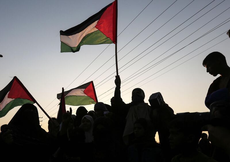 Palestinian protesters wave national flags at sunset during a demonstration near the Erez crossing with Israel. AFP