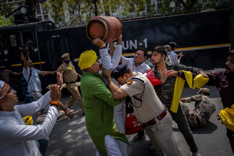 A Delhi police officer tries to stop an opposition Congress party supporter during a protest against rising inflation and price hikes of essential commodities in New Delhi, India. AP