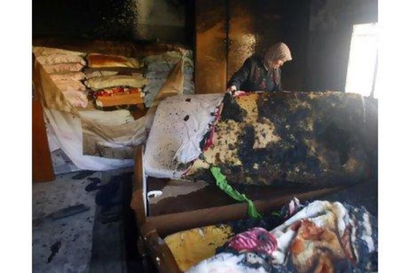 A Palestinian woman holds a burnt mattress as she surveys the damage caused by Jewish settlers throwing a petrol bomb into her house late on Monday night near Nablus, in the West Bank.