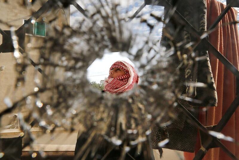 A boy is pictured through a bullet hole in a window of the building where suspected militants were hiding out in the Jordanian village of Garifla, near the southern city of Karak, on December 21, 2016. Muhammad Hamed/Reuters