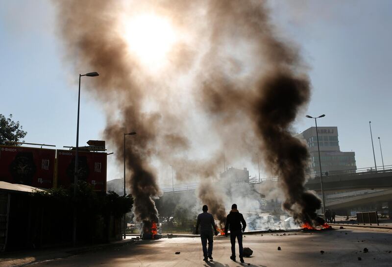 A Lebanese protester walks past burning tyres during ongoing anti-government demonstrations in Beirut. AP Photo