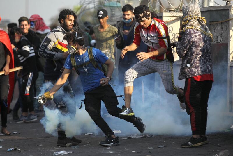 An Iraqi protester grabs a tear gas canister fired by riot police amid clashes following a demonstration at Baghdad's Tayaran Square, east of Tahrir Square. AFP