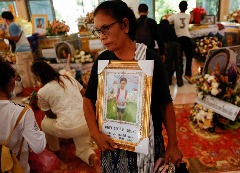A woman holds a picture of a victim as people pray at Wat Rat Samakee temple. Reuters