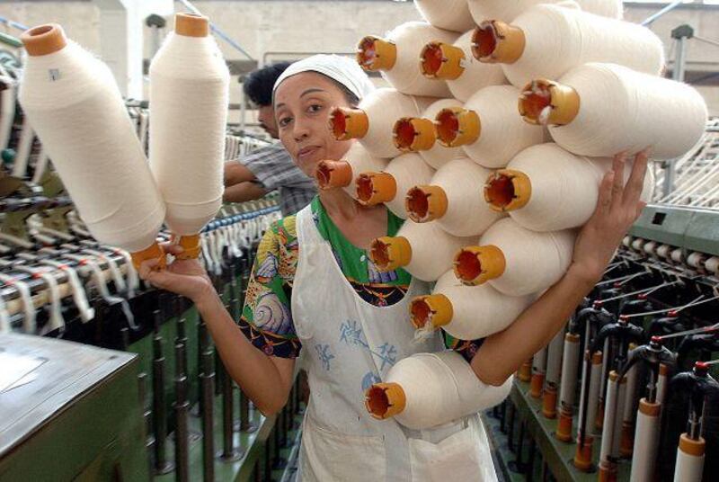 A worker carries yarn at a textile factory in Hefei, China. A drop in demand for Chinese products could dampen the global recovery.