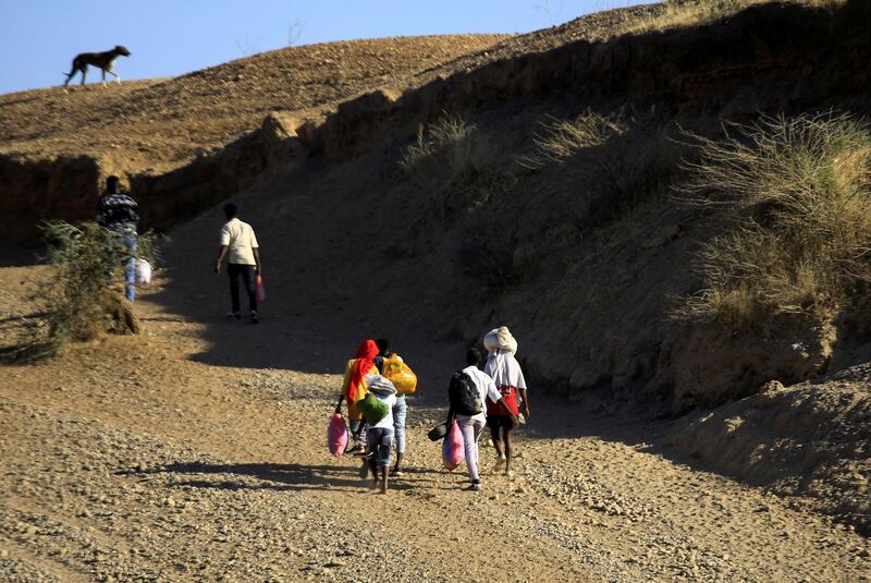 FILE PHOTO: Ethiopians, who fled the ongoing fighting in Tigray region, carry their belongings after crossing the Setit River on the Sudan-Ethiopia border, in the eastern Kassala state, Sudan December 16, 2020. REUTERS/Mohamed Nureldin Abdallah/File Photo