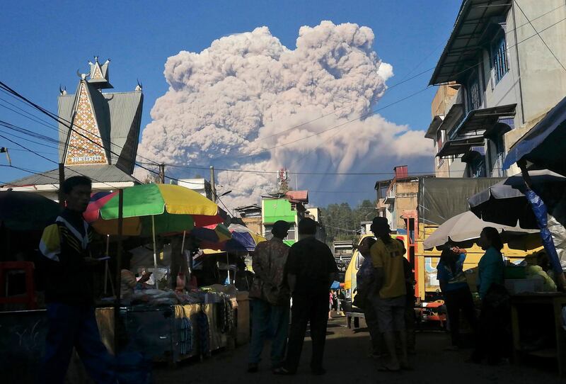 People look on as Mount Sinabung, a 2,600-metre in Indonesia, spews volcanic material thousands of metres into the air. AP