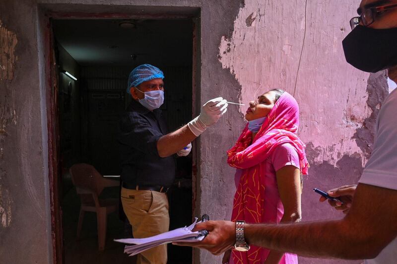 A medical worker takes a swab sample of a woman for a Covid-19 PCR test at a testing centre in Ghaziabad, India. AFP