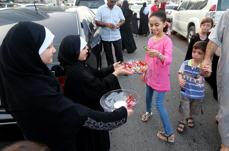 Children distribute chocolates after Eid prayers at the Al Noor Mosque in Sharjah. Satish Kumar / The National