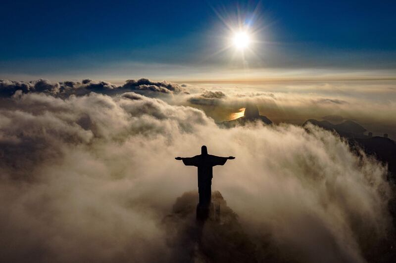 The sun rises over the Christ the Redeemer statue in Rio de Janeiro.  Christ the Redeemer is celebrating its 90th anniversary in October 2021 and is being restored to ensure that it looks its best for the public and visiting tourists. AFP