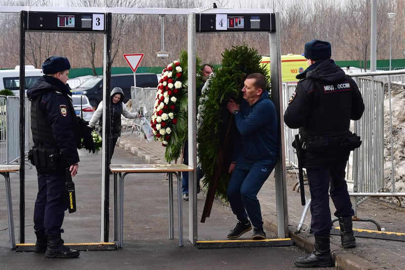 A wreath is brought through a metal detector security gate. AFP