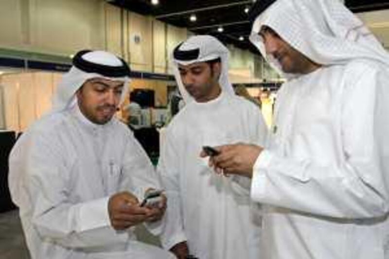 United Arab Emirates - Abu Dhabi - May 26 - 2009 : Emirati men check a cell phone at Etisalat showroom during MECOM 2009 , Middle East Comunications, at Abu Dhabi National Exhibition Centre. ( Jaime Puebla / The National ) *** Local Caption ***  JP 17 MECOM.jpgJP 17 MECOM.jpg