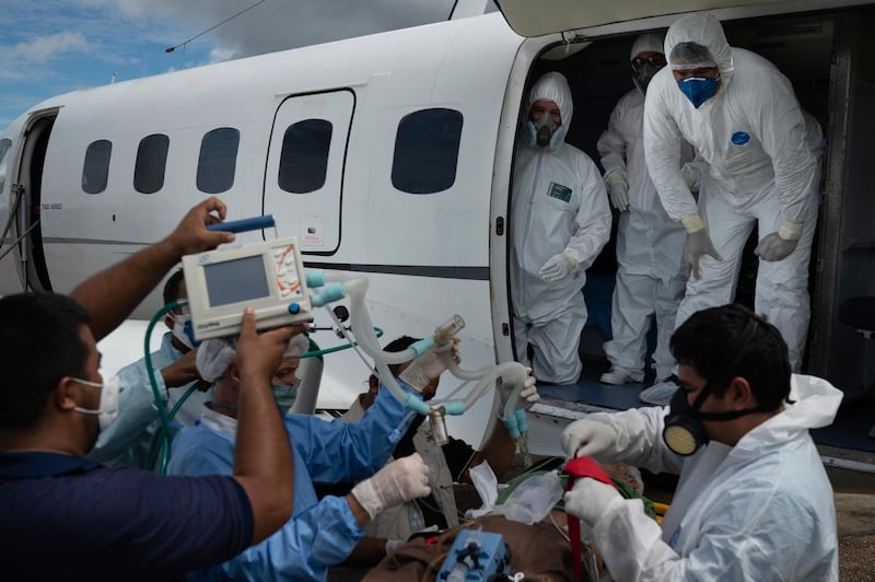 Health workers prepare to move 89-year-old Covid-19 patient Sildomar Castelo Branco into an aircraft as he is transferred from Santo Antonio do Içá to a hospital in Manaus, Brazil. AP Photo
