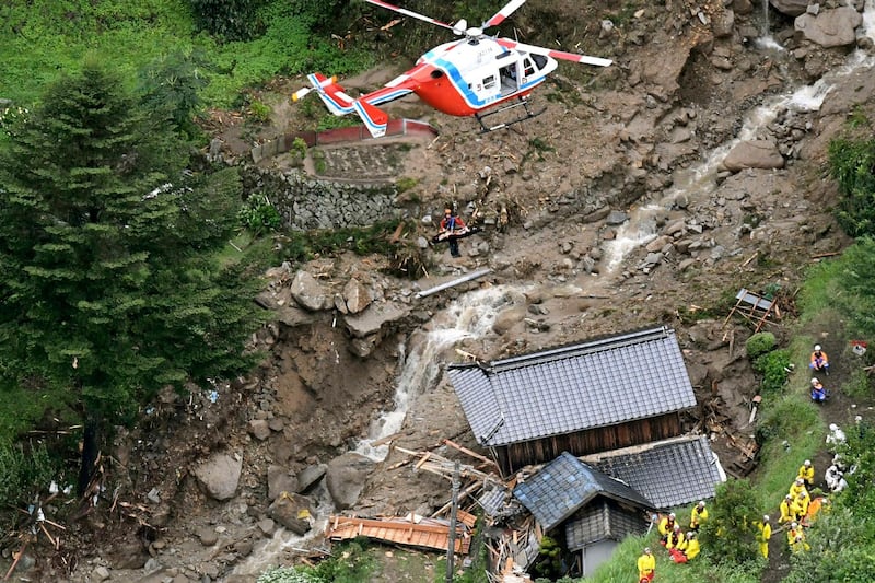 A rescue helicopter hovers over damaged buildings after a landslide caused by heavy rains in Iwakuni, Yamaguchi prefecture, southwestern Japan. AP Photo