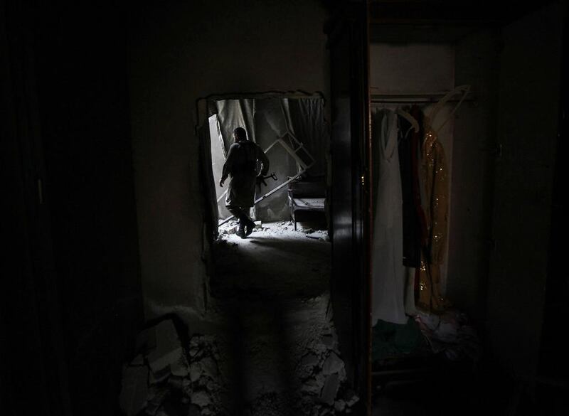 A Free Syrian Army fighter carries his weapon as he walks inside a house near the Nairab military airport. Hamid Khatib / Reuters