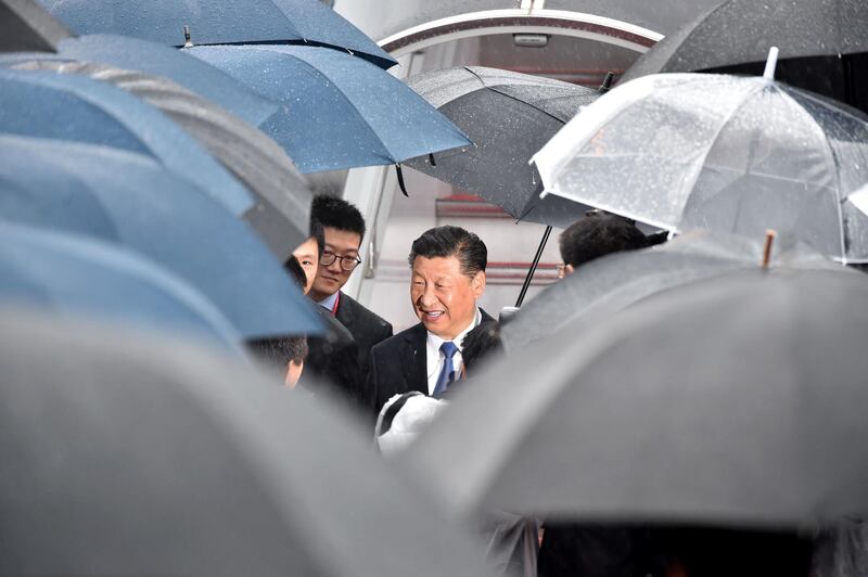 Chinese President Xi Jinping seen through a huddle of umbrellas. AFP