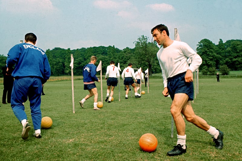 England's Jimmy Greaves dribbles through a set of poles ahead of the 1966 World Cup squad. PA