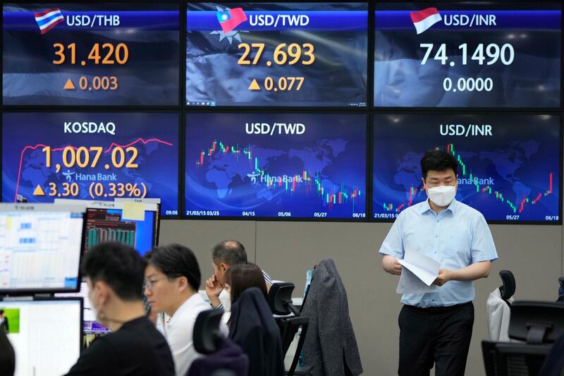 A currency trader passes by screens showing foreign exchange rates at the foreign exchange dealing room of the KEB Hana Bank headquarters in Seoul, South Korea, Friday, June 18, 2021. Asian shares mostly rose Friday, as investors digested the latest message from the U.S. Federal Reserve on raising short-term interest rates by late 2023. (AP Photo/Ahn Young-joon)