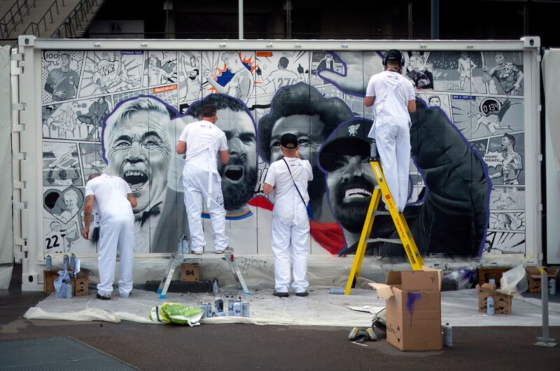 Artists from MurWalls work on a piece celebrating the defining moments of the Champions League season outside the Stade de France on Thursday, May 26, 2022. AP