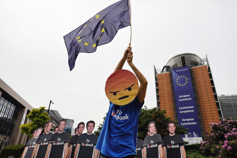 A protester waves a European Union (EU) flag beside cutouts of Facebook Inc. Chief Executive Officer Mark Zuckerberg during a protest outside the Berlaymont building ahead of his testimony to the European Union (EU) parliament in Brussels, Belgium, on Tuesday, May 22, 2018. Zuckerberg will tout the companys investment in Europe and again take responsibility for privacy failures, according to testimony prepared for an appearance Tuesday in front of the regions parliament. Photographer: Dario Pigantelli/Bloomberg