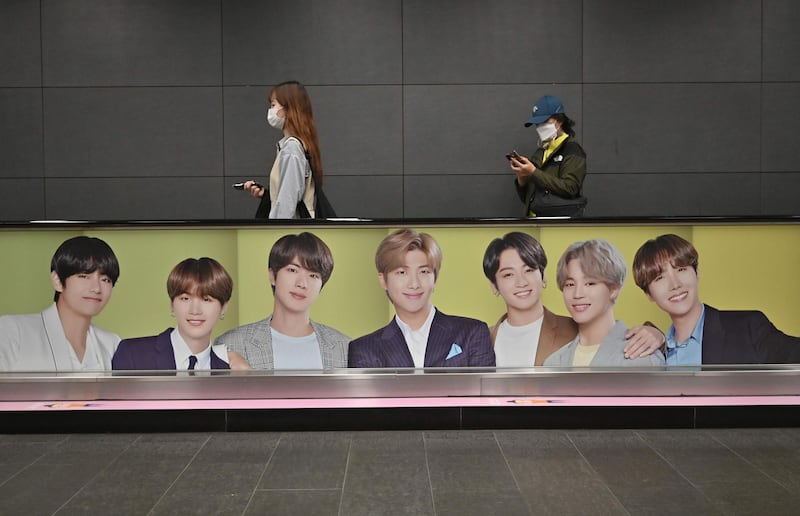 People walk past a commercial poster showing BTS members at a subway station in Seoul. AFP