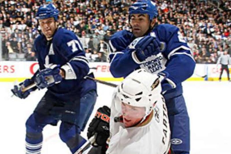 Ryan Carter, in white,  of the Ducks, is checked by Jamal Mayers and Pavel Kubina of the Toronto Maple Leafs.