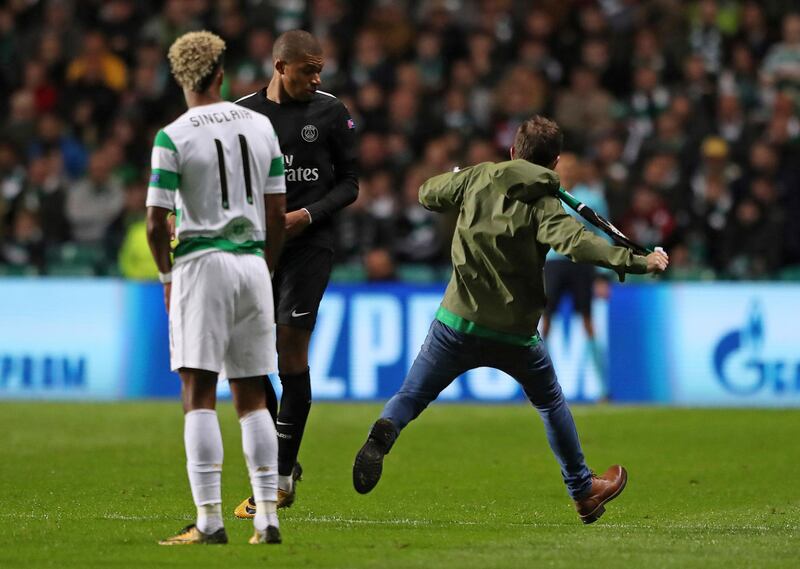 A fan runs by Paris Saint-Germain's Kylian Mbappe-Lottin, with Celtic's Sinclair, left, during the Champions League, Group B soccer match at Celtic Park in Glasgow, Scotland, Tuesday Sept. 12, 2017. (Andrew Milligan/PA via AP)