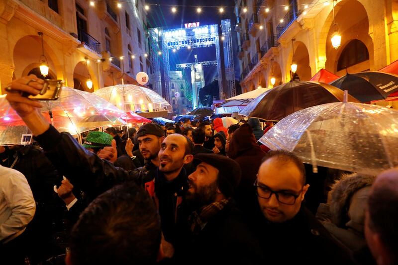 People take selfies as they celebrate in the rain ahead of the New Year at down town Beirut,Lebanon December 31, 2017. REUTERS/ Jamal Saidi