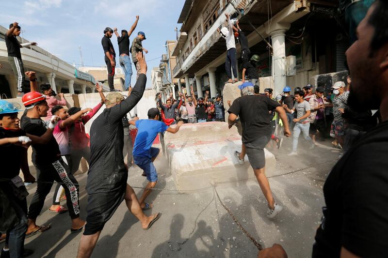 Demonstrators push down concrete barriers during the anti-government protests in Baghdad. Reuters