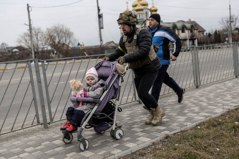 A Ukrainian soldier helps a family fleeing from Irpin. Reuters