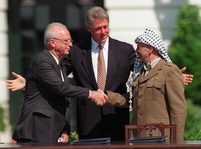 Israeli Prime Minister Yitzhak Rabin, left, and PLO chairman Yasser Arafat, right, shake hands as President Bill Clinton presides over the ceremony marking the signing of the 1993 peace accord between Israel and the Palestinians on the White House lawn, Sept. 13, 1993. (AP Photo/Ron Edmonds)