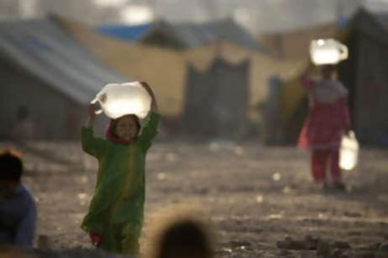Pakistani girls from the Bajur tribal region carry water collected from a water point at the Katcha Garhi camp in Peshawar, Pakistan, on Oct 19 2008.