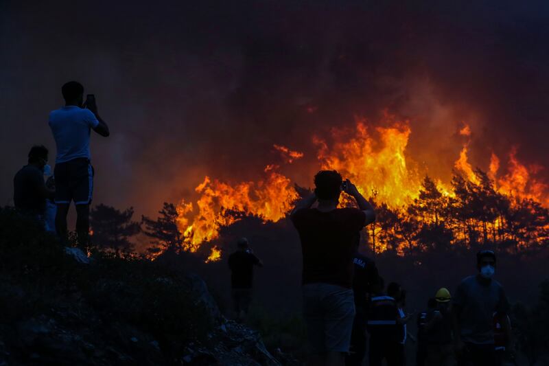 People watch a wildfire near the village of Akcayaka in Milas, Mugla, south-west Turkey.