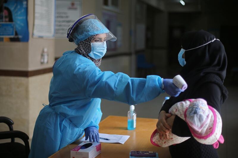 A health worker checks the temperature of a newborn Palestinian baby before being administered a vaccine at a United Nations-run clinic during the coronavirus disease outbreak, in the southern Gaza Strip. Reuters