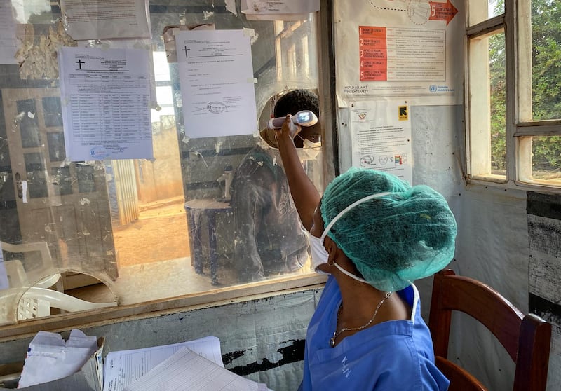 A medical worker checks a person's temperature at the Matanda Hospital in Butembo, where the first case of Ebola died, in the North Kivu province of Congo, February 11, 2021. AP Photo
