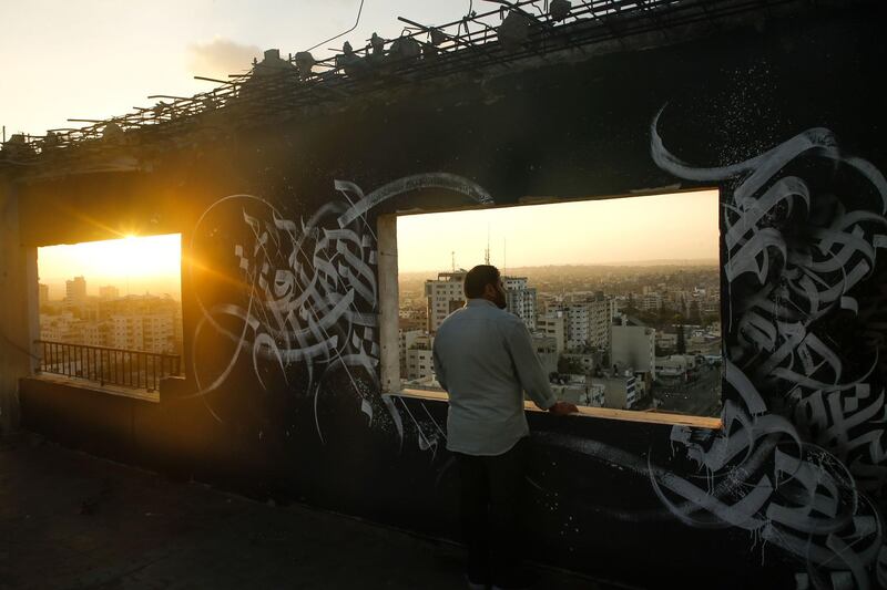A Palestinian man gazes at Gaza City from a rooftop ornated with Arabic calligraphy.  AFP