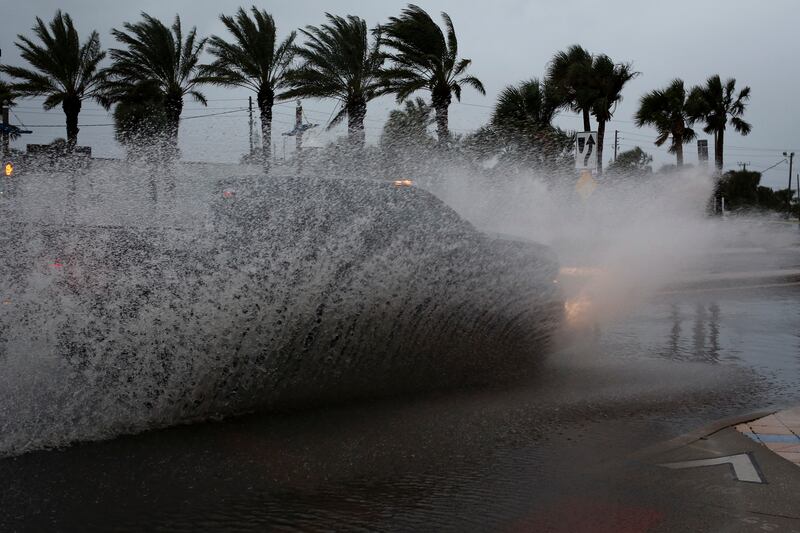 A car drives along a flooded street ahead of the expected arrival of Hurricane Nicole, in Daytona Beach, Florida. Reuters