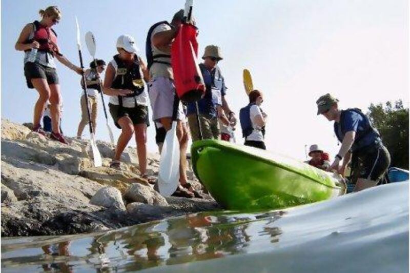 A tour guide, standing in the water, helps kayakers to navigate the Abu Dhabi mangroves. Ana Bianca Marin for The National