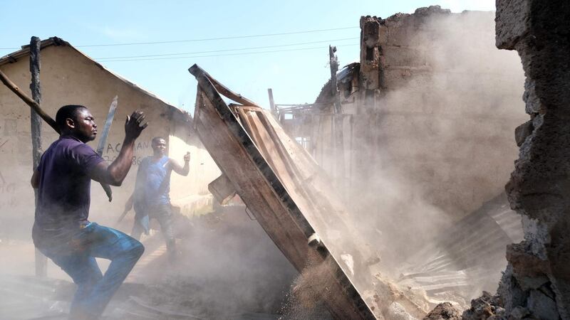 Two men attempt to bring down a wall during clashes between youths in Apo, Abuja, Nigeria following the ongoing demonstrations against the unjustly brutality of the Nigerian Police Force Unit, the Special Anti-Robbery Squad (SARS).  AFP