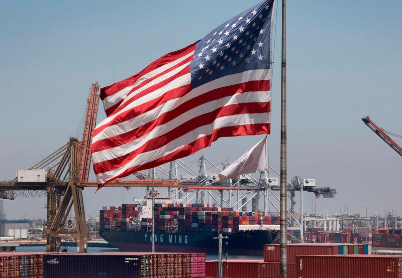 =(FILES) In this file photo taken on August 1, 2019 the US flag flies over a container ship unloading it's cargo from Asia, at the Port of Long Beach, California. President Donald Trump hit back at China on August 23, 2019, in their mounting trade war, raising existing and planned tariffs in retaliation for Beijing's announcement earlier in the day of new duties on American goods. / AFP / Mark RALSTON
