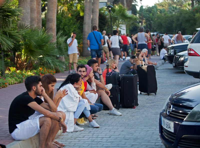 Guests of the Acapulco hotel in Kyrenia (Girne) in the self-proclaimed Turkish Republic of Northern Cyprus (TRNC) north of the divided Cypriot capital Nicosia, stand outside with their belongings after the building was damaged when a military depot exploded nearby, on September 12, 2019. Multiple explosions at a Turkish military base in northern Cyprus damaged a hotel in a neighbouring holiday resort early Thursday, prompting the evacuation of terrified tourists, officials said. / AFP / Birol BEBEK
