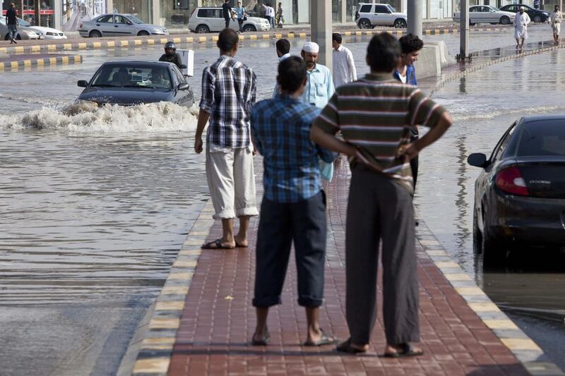 Pedestrians have a think about getting their feet wet in Sharjah. Antonie Robertson / The National
