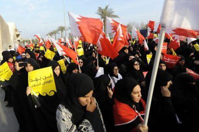 Female protesters holding placards that read in Arabic 'the people will not be silenced', rally during in an opposition march in Sanabis village, on the outskirts of Manama on Tuesday.