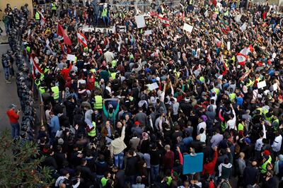 Anti-government protesters chant slogans as riot police stand guard in front of the government building, in central Beirut, Lebanon, Sunday, Dec. 23, 2018. Hundreds of Lebanese protested against deteriorating economic conditions as politicians are deadlocked over forming a new government. (AP Photo/Bilal Hussein)