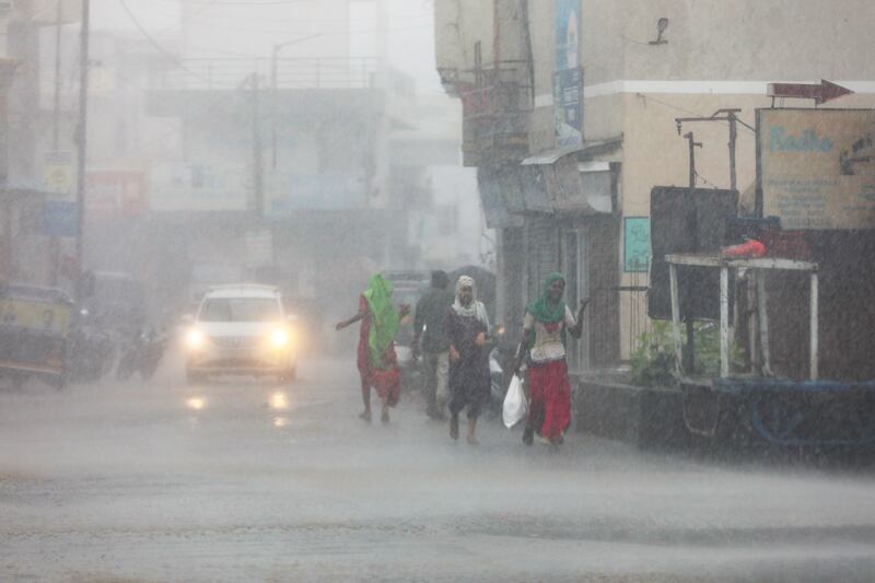 People walk on a street during heavy rain in Mandvi in the western state of Gujarat, India, as Cyclone Biparjoy makes landfall. EPA