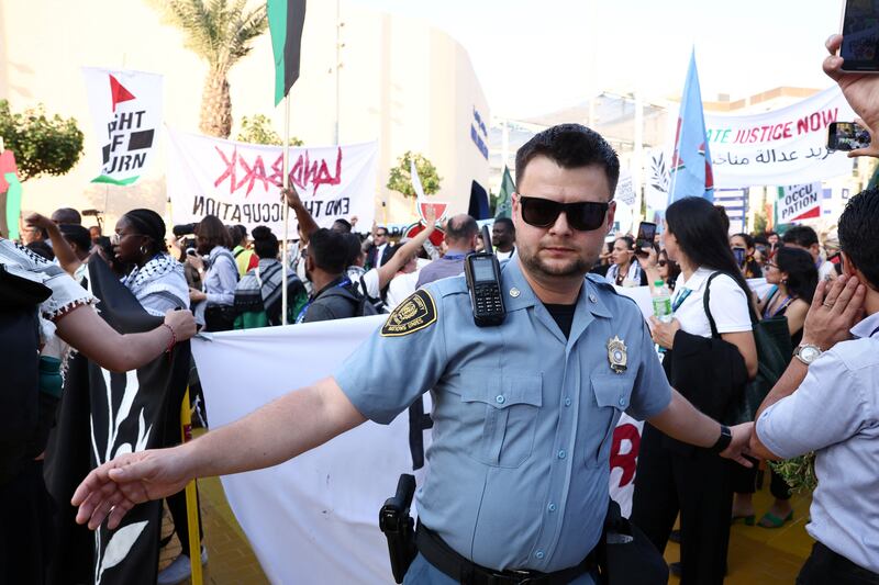 UN security officer watches on as a crowd march through the Cop28 site in Dubai. Reuters