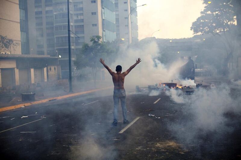 A demonstrator raises his arms toward the Bolivarian National Police as they fired tear gas and a water canon on February 19, 2014, in the Altamira neighbourhood of Caracas, Venezuela. National security forces dispersed anti-government demonstrators who tried to block the city’s main motorway on Wednesday evening. Rodrigo Abd / AP photo